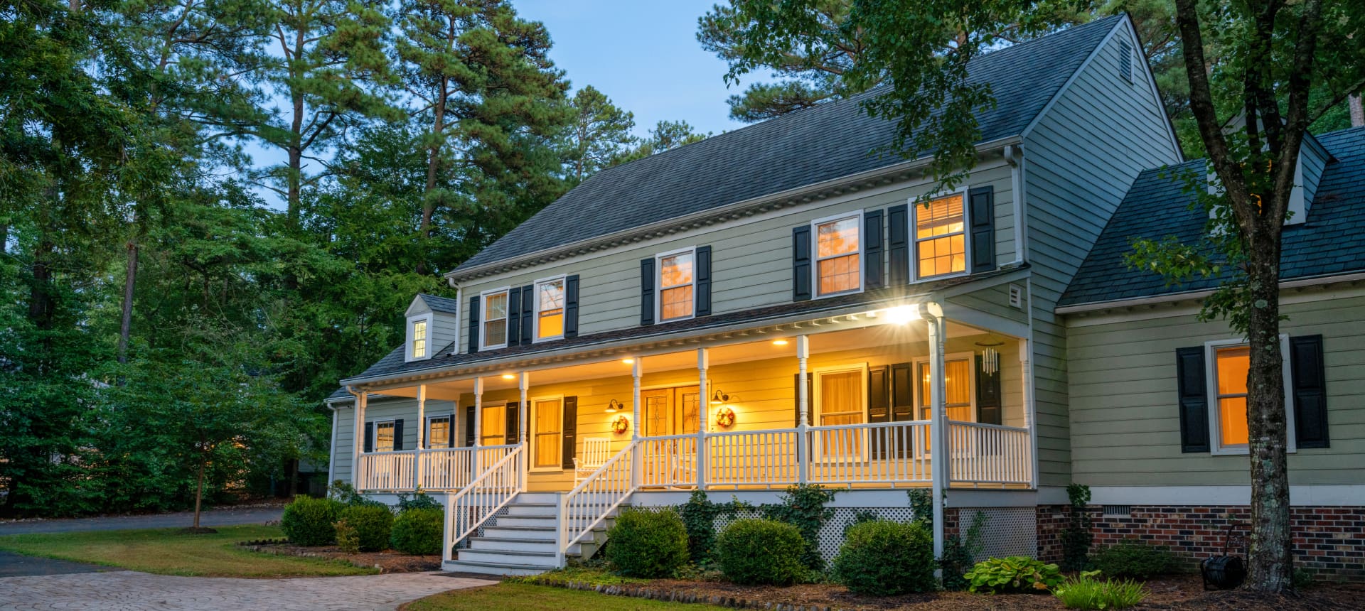 A charming two-story house with a porch lit warmly at dusk.